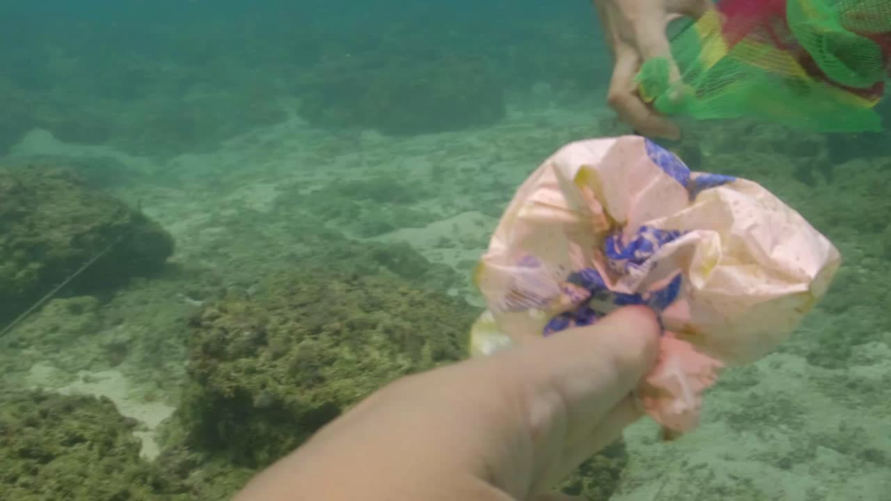 Scuba Divers Picking Up Littered Plastic Garbage Under The Ocean. Marine Pollution. underwater