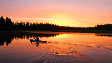 person kayaking on a lake at sunset