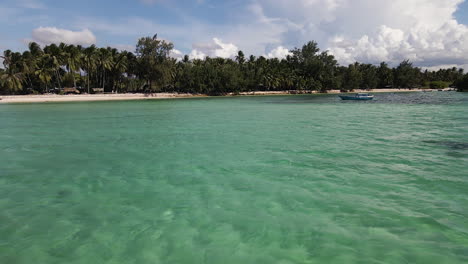 Flying-Towards-The-Tropical-Shore-With-Some-People-Enjoying-Swimming-In-Turquoise-Waters-Of-Sumba-Island-In-Indonesia