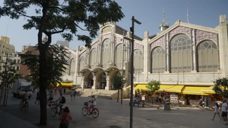 Ciclistas-Y-Personas-A-La-Entrada-Del-Mercado-Central-De-Valencia,-España,-Mañana-De-Principios-De-Verano