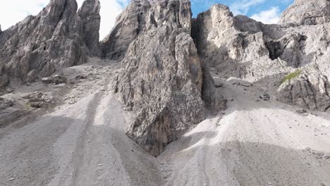 vista a nivel del suelo de las dolomitas que muestran formaciones rocosas distintas, caminos de grava y vegetación escasa