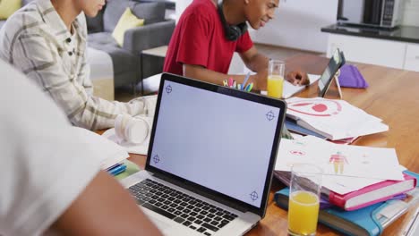 Three-happy-diverse-male-teenage-friends-using-laptop-with-copy-space-at-home,-slow-motion