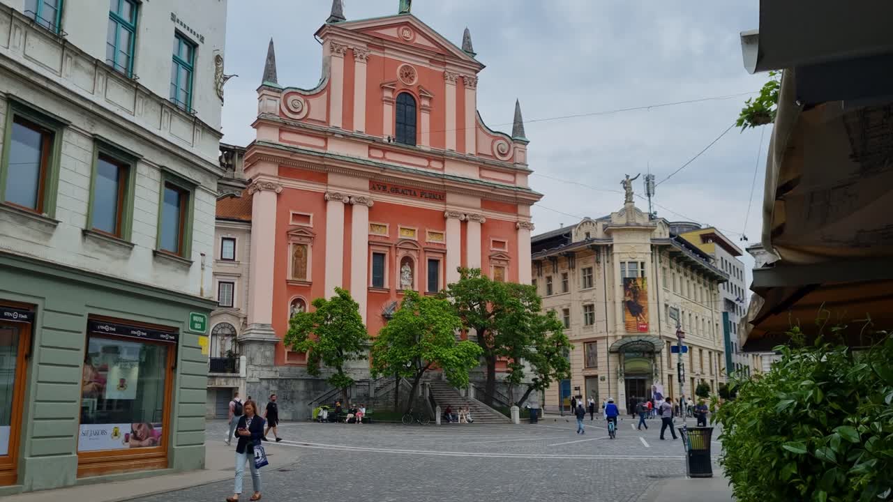 Pedestrians and cyclists passing in front of the Church of the Annunciation or Franciscan Church on Preseren square in the center of Ljubljana Slovenia on an cloudy spring day