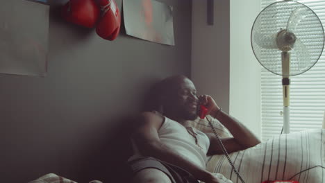 african american man talking on phone on bed in morning