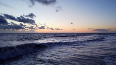 Drone-shot-slow-moving-over-ocean-waves-with-sunset-on-endless-horizon