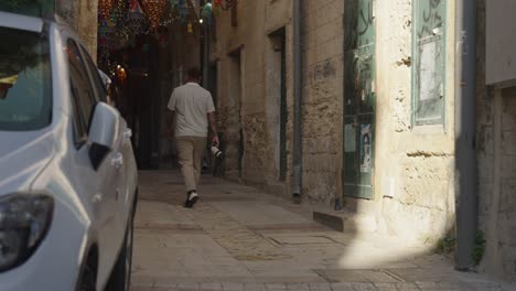 Male-photographer-walks-in-narrow-covered-alley-in-old-town,-Nazareth