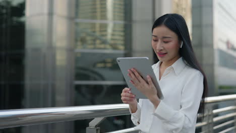Young Asian Businesswoman Using Tablet for Video Call in Urban Setting