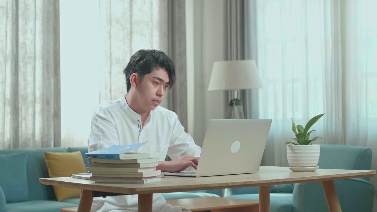 Young Man Studying at Home with Laptop