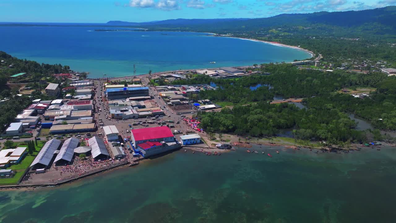 Wewak Sundaun fish Market Wewak Hill buildings cars traffic people Boram road Papua New Guinea aerial drone downtown coastal town city center Dogreto Bay sunny morning blue sky forward pan up