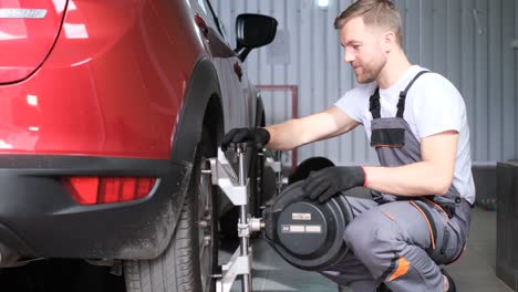 mechanic performing wheel alignment on a red car