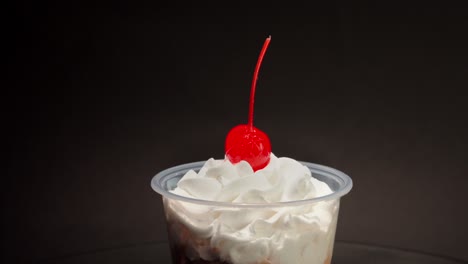 close up detail shot chocolate cream cup parfait cherry on top spinning in turntable with black background copa nevada