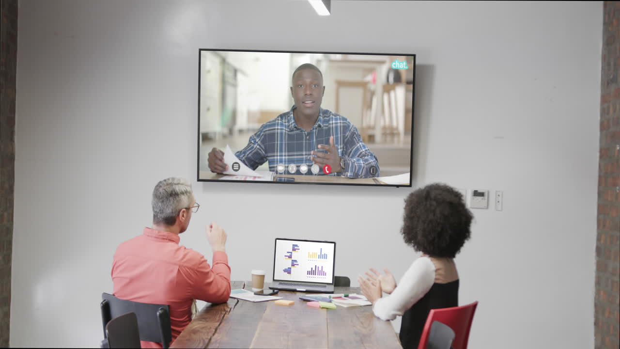 gente de negocios en videoconferencia con una colega afroamericana en la pantalla de televisión