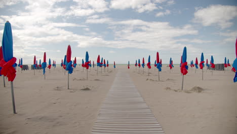 endless wooden pathway in sandy beach with closed umbrellas