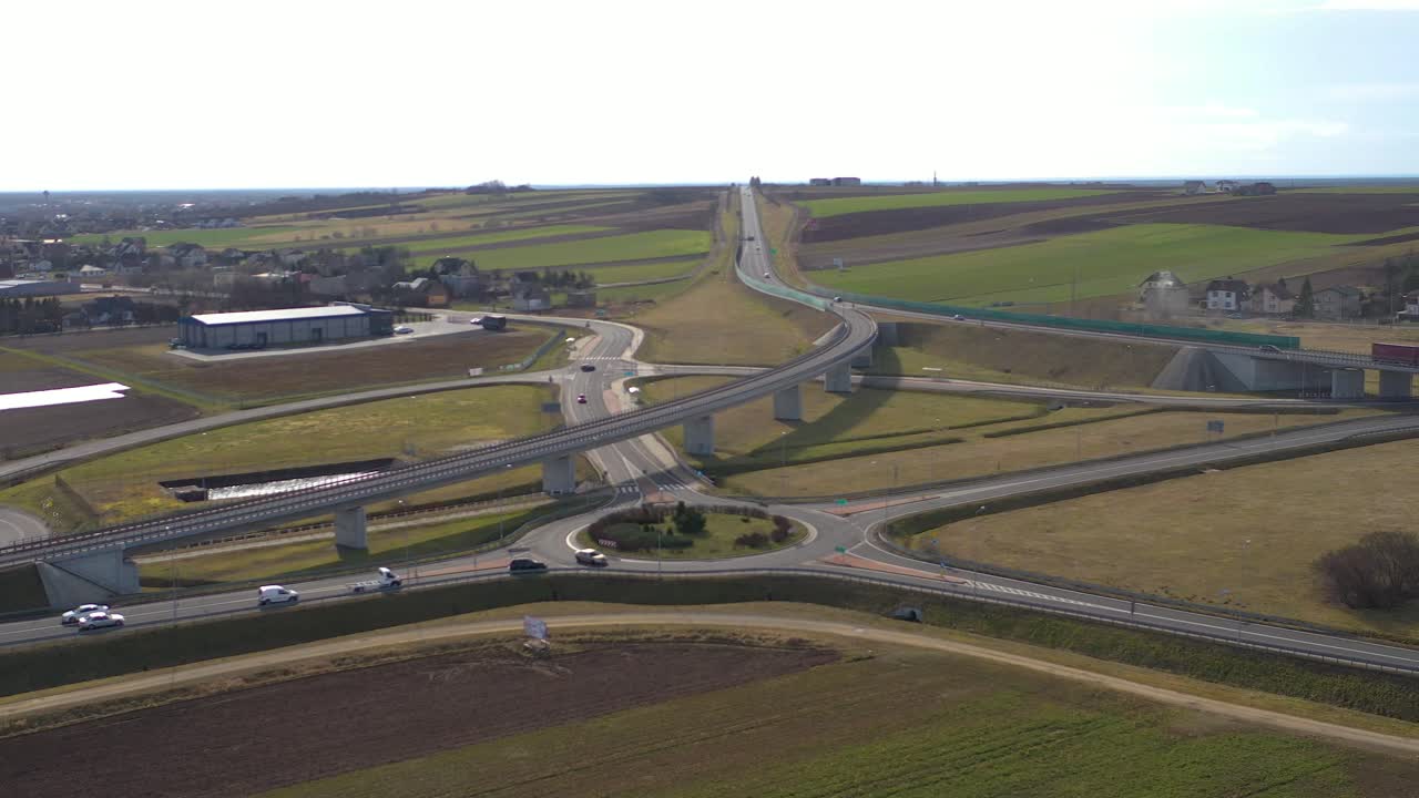 Aerial shot of the vehicles approaching a roundabout in a highway on a bright sunny afternoon