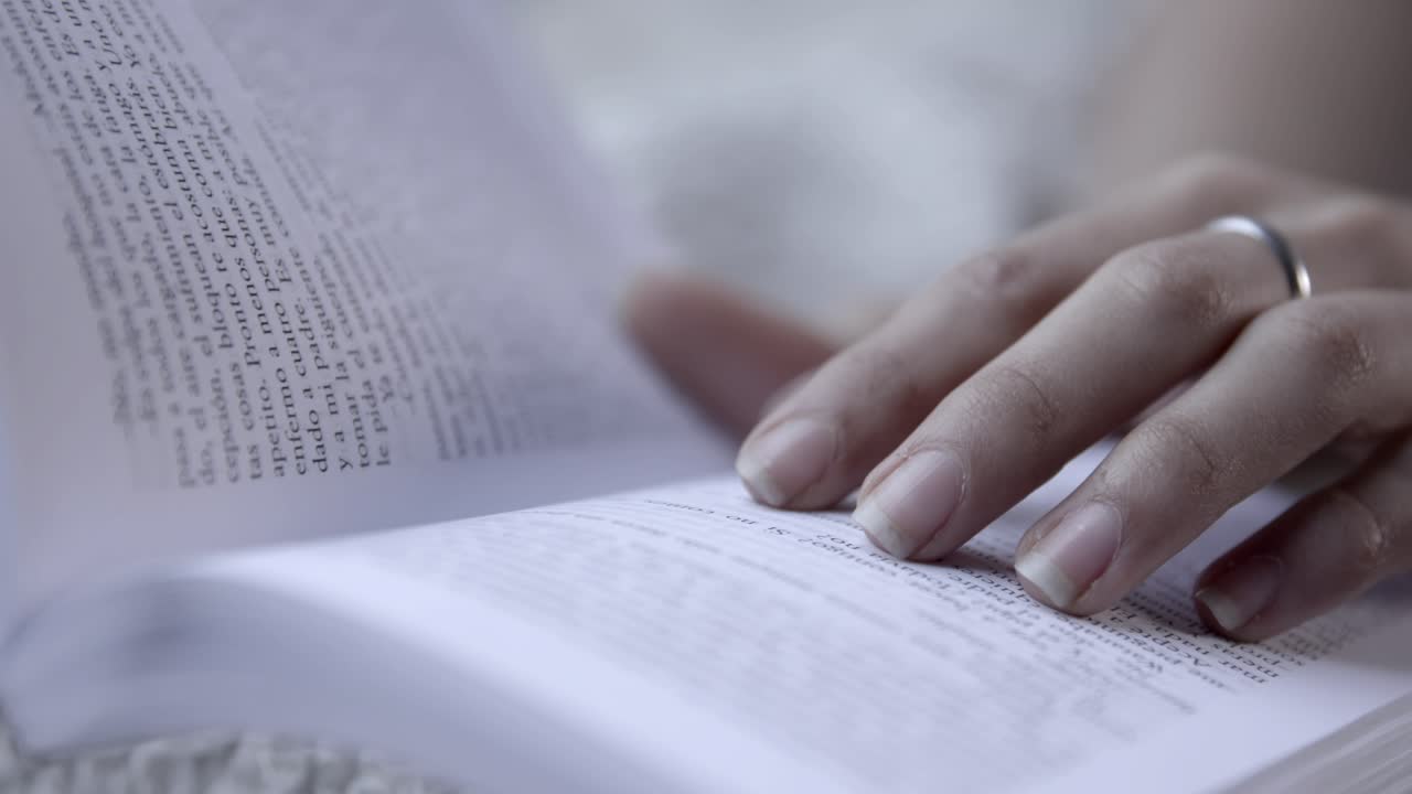 Close Up of a Person's Hand Reading a Book and Turning Pages