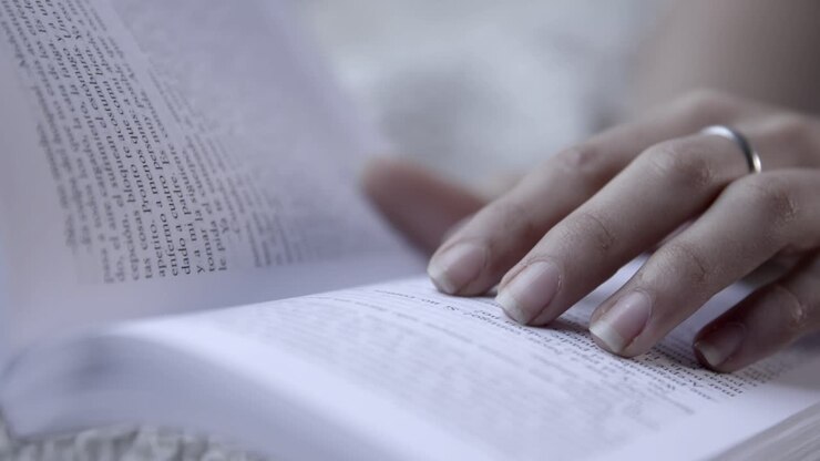 Close Up of a Person's Hand Reading a Book and Turning Pages