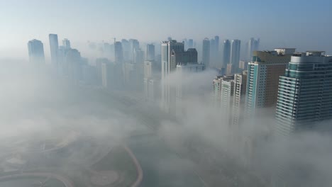 Niebla-En-Los-Emiratos-árabes-Unidos:-Vista-Aérea-De-La-Niebla-Sobre-El-Lago-Khalid-De-Sharjah,-Horizonte-De-Sharjah-Cubierto-De-Niebla-Matutina-De-Invierno,-Emiratos-árabes-Unidos,-Imágenes-De-Drones-De-4k