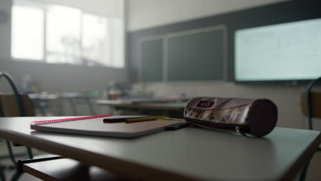 libro de notas, bolígrafos y lápices en el escritorio en el aula. suministros escolares en la mesa