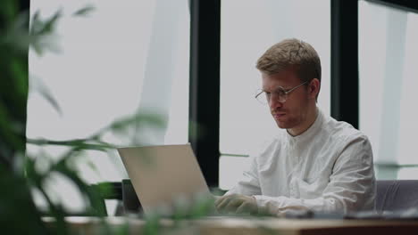 attentive millennial male manager employee busy at telework at quarantine time study documents in corporate network from home pc. concentrated young man specialist doing remote computer work on laptop