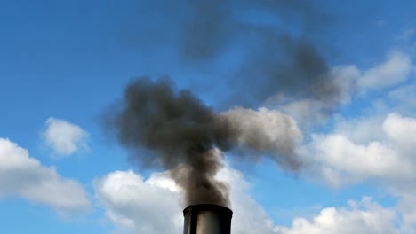 from a pipe of the plant lets out black smoke with soot in air and pollution it