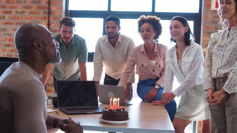 Personal-Celebrando-El-Cumpleaños-De-Un-Colega-Masculino-En-Una-Oficina-Multicultural-Con-Pastel