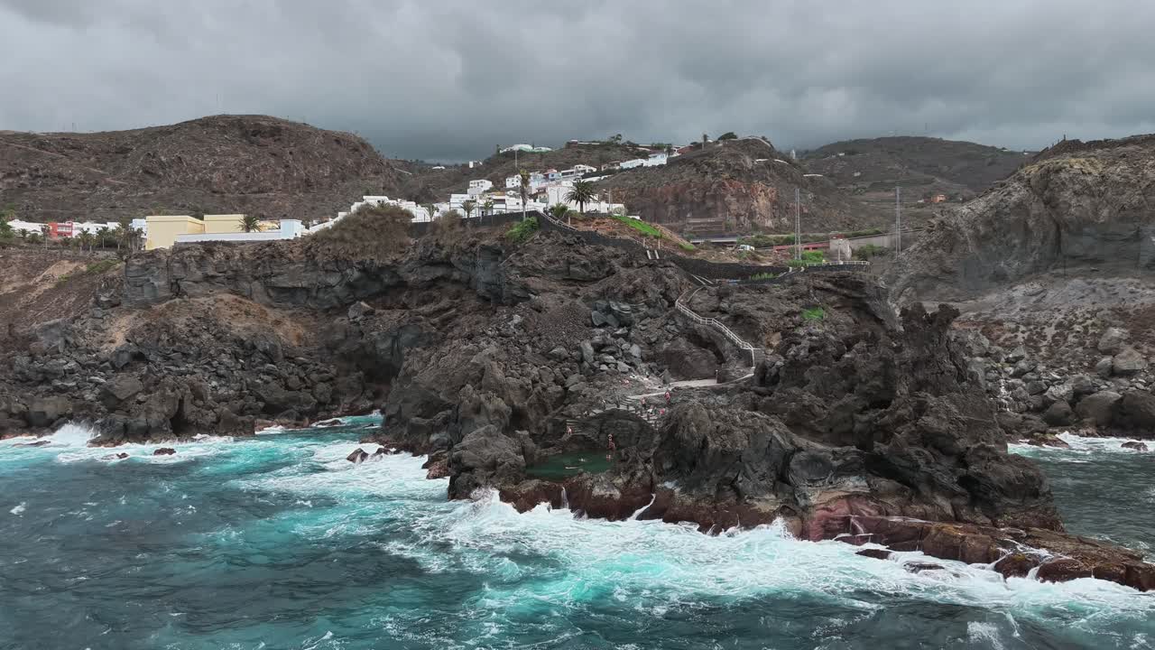Aerial view of Tenerife rugged coastline and coastal pool under cloudy sky