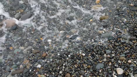 Close-up-of-waves-gently-crashing-onto-a-rocky-shore