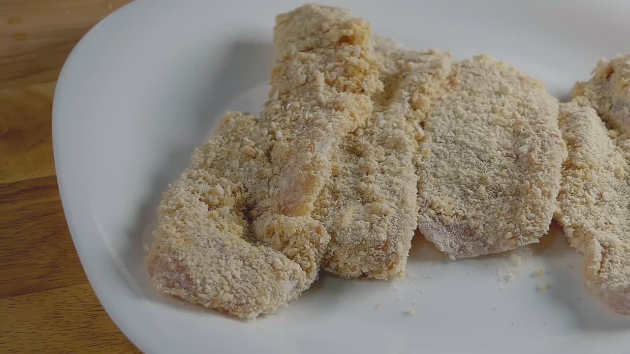 집 부엌에서 빵가루를 입혀 요리할 준비가 된 닭 가슴살 조각의 슬라이더 샷