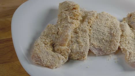 toma deslizante de trozos de pechuga de pollo empanados y listos para cocinar en una cocina casera