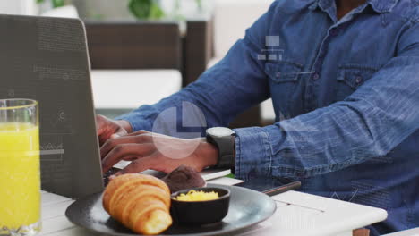 Animation-of-multiple-icons-and-graphs-over-biracial-man-working-on-laptop-in-office