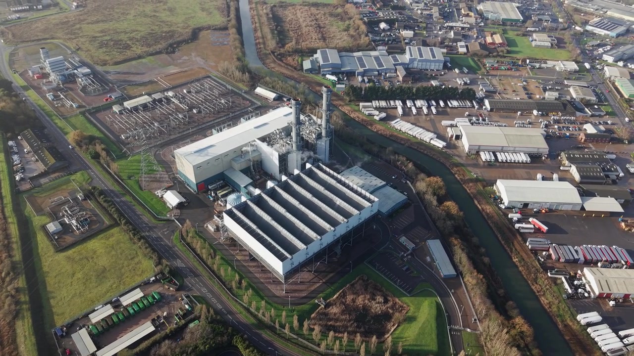 Aerial view tracking across heavy industry chimneys and exhaust cooling towers at an energy plant
