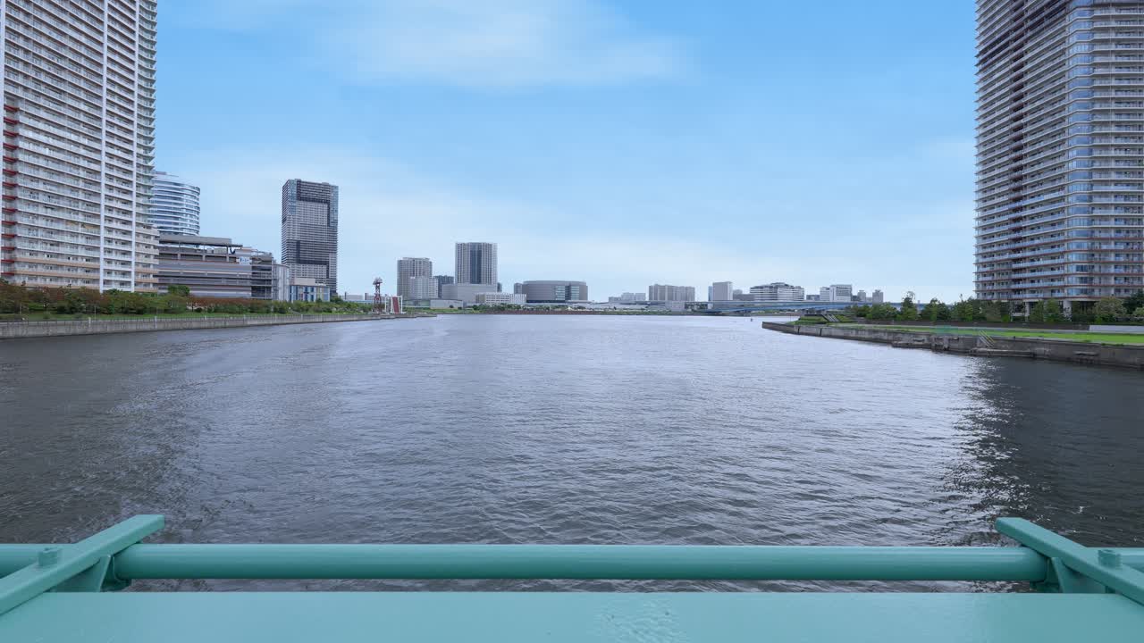 A peaceful wide shot of the Tokyo Bay area and distant cityscape, viewed from the former Harumi Railway Bridge railing
