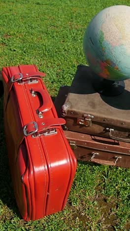 vintage suitcases and globe on grass