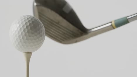 Close-up-of-golf-tee,-ball-and-club-on-white-background,-copy-space,-slow-motion