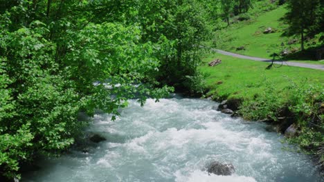 Tilt-Down-View-of-Rushing-Blue-Water-in-Swiss-Stream