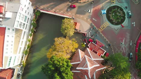 focus on buildings and river crossed by street and roundabout in malacca city