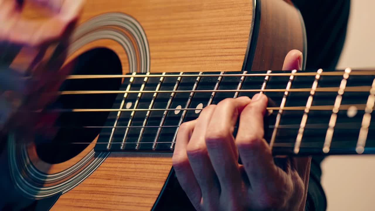 primer plano de manos tocando una guitarra bajo acústica