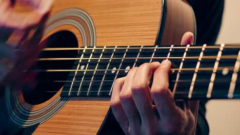 primer plano de manos tocando una guitarra bajo acústica