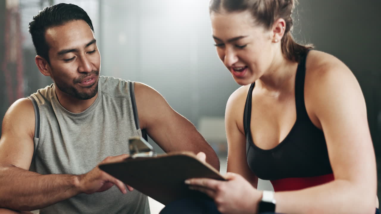 hombre, mujer y bloc con escritura en el gimnasio