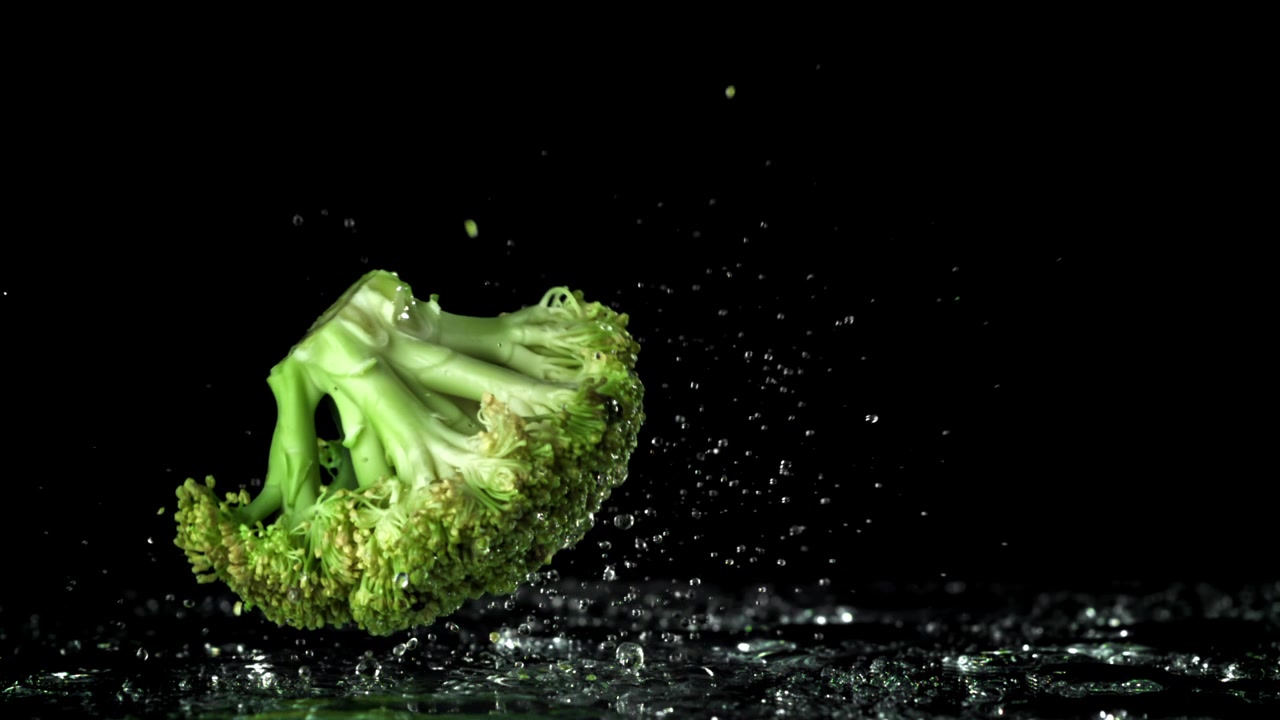 Broccoli freschi che cadono nell'acqua con schizzi al rallentatore
