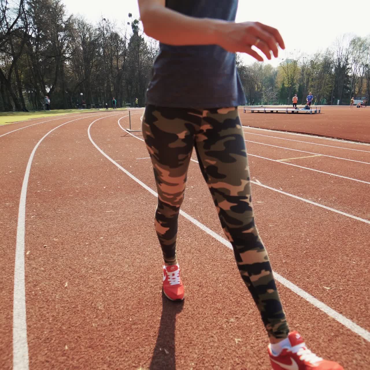 Young fit woman working out by running on urban stadium track. Runner on the running track.