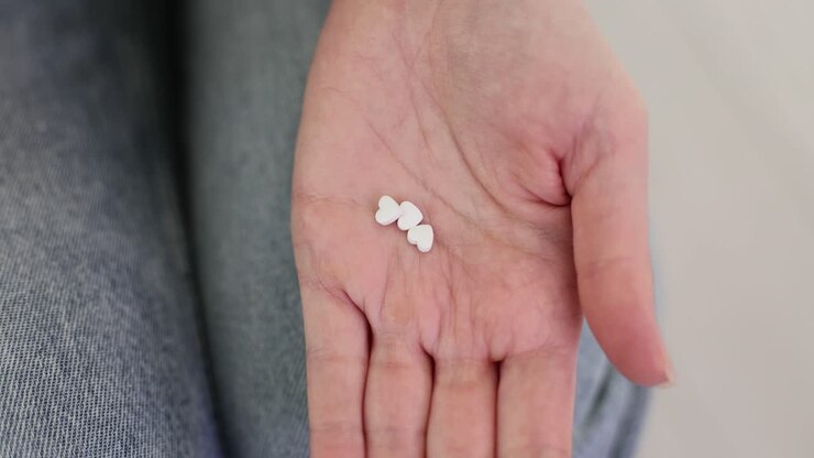 Heart-shaped pills being poured into a hand