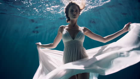 ethereal woman in flowing white dress underwater