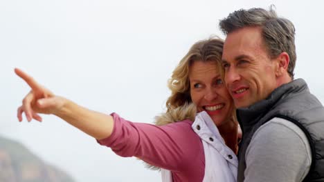happy mature couple pointing at view