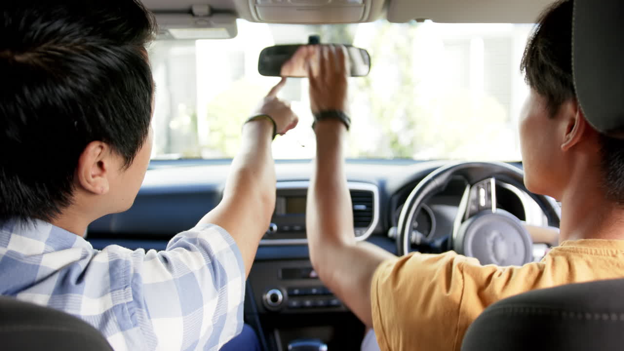 Driving car, asian father and son talking and gesturing in front seat, daytime journey