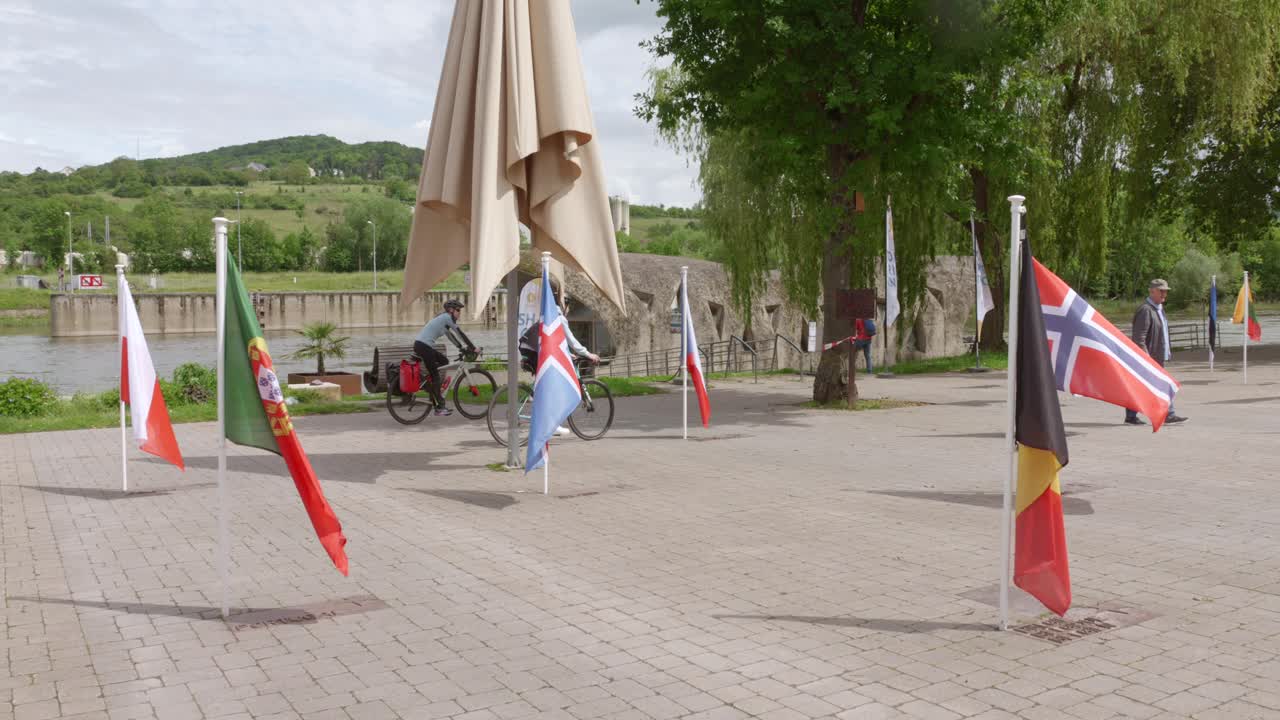 Flags from various nations on display in Schengen, Luxembourg near the river and town square
