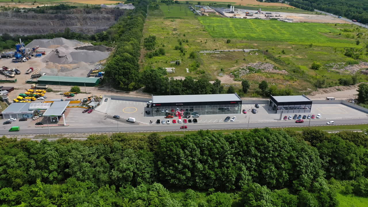 Outskirts of the city where new car dealership is opened. Lush greenery and industrial area around. Top perspective.