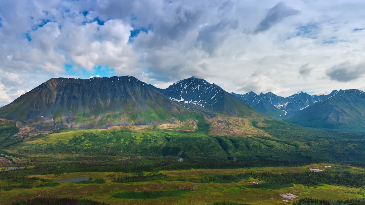 Amazing mountains with little snow on the slopes. Sky covered with clouds above. Spectacular nature of Alaska, USA. Aerial view