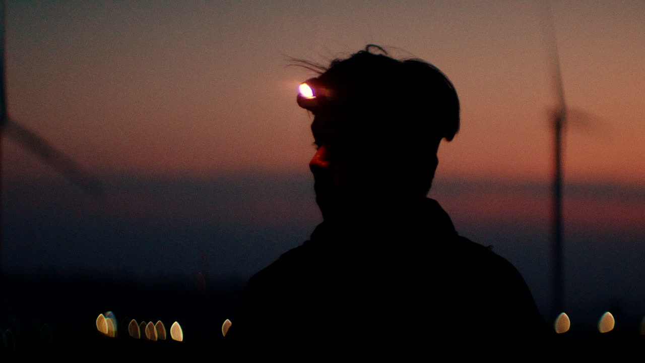 Silhouette of person with headlamp at sunset