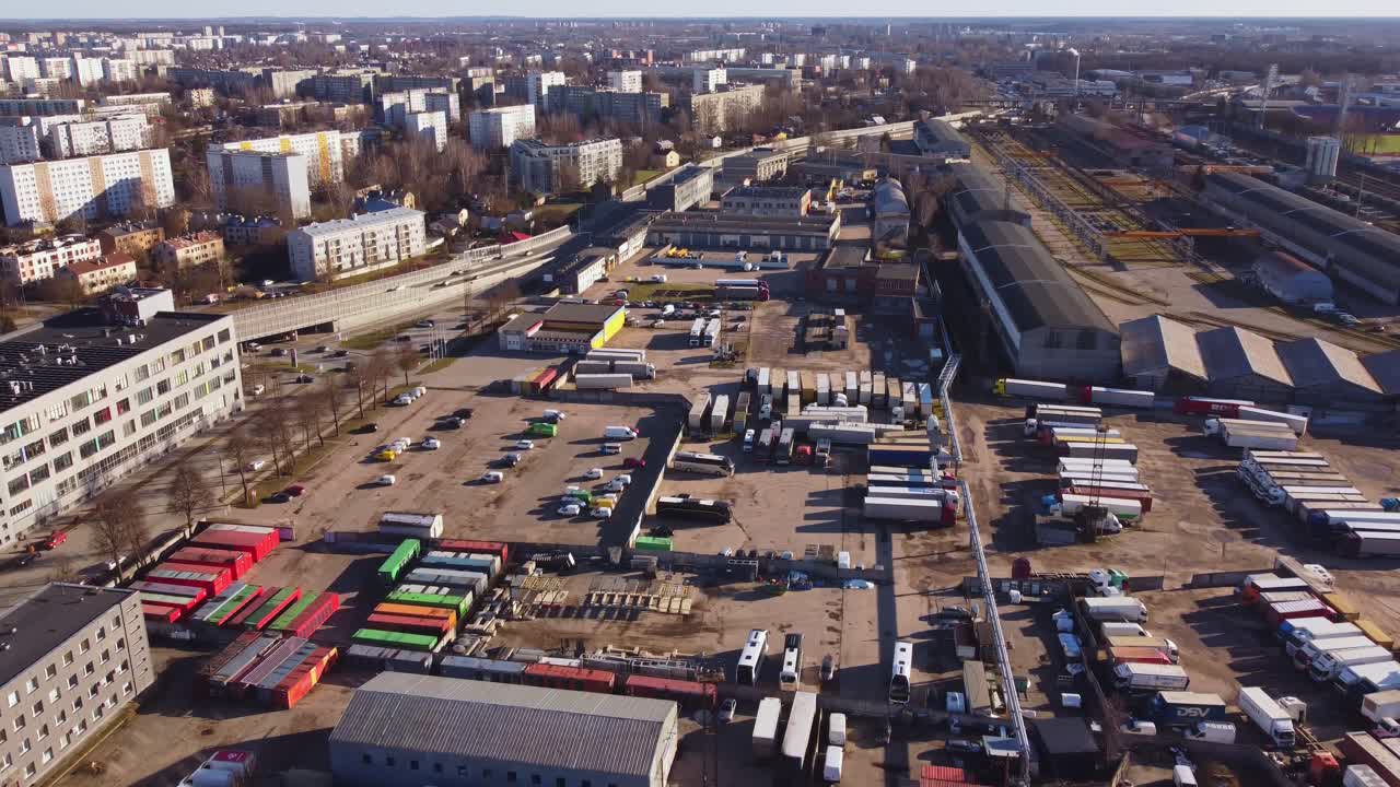 Aerial drone view of urban logistics hub with trucks, containers and warehouses. Industrial area with businesses in a city from above.